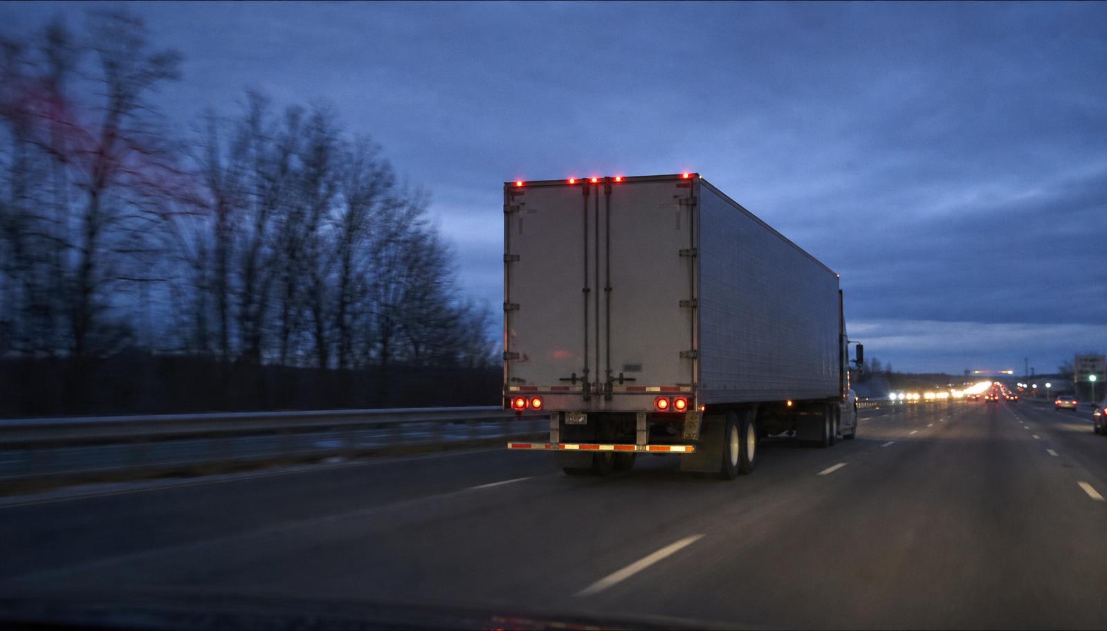Caminhão em movimento na rodovia ao anoitecer